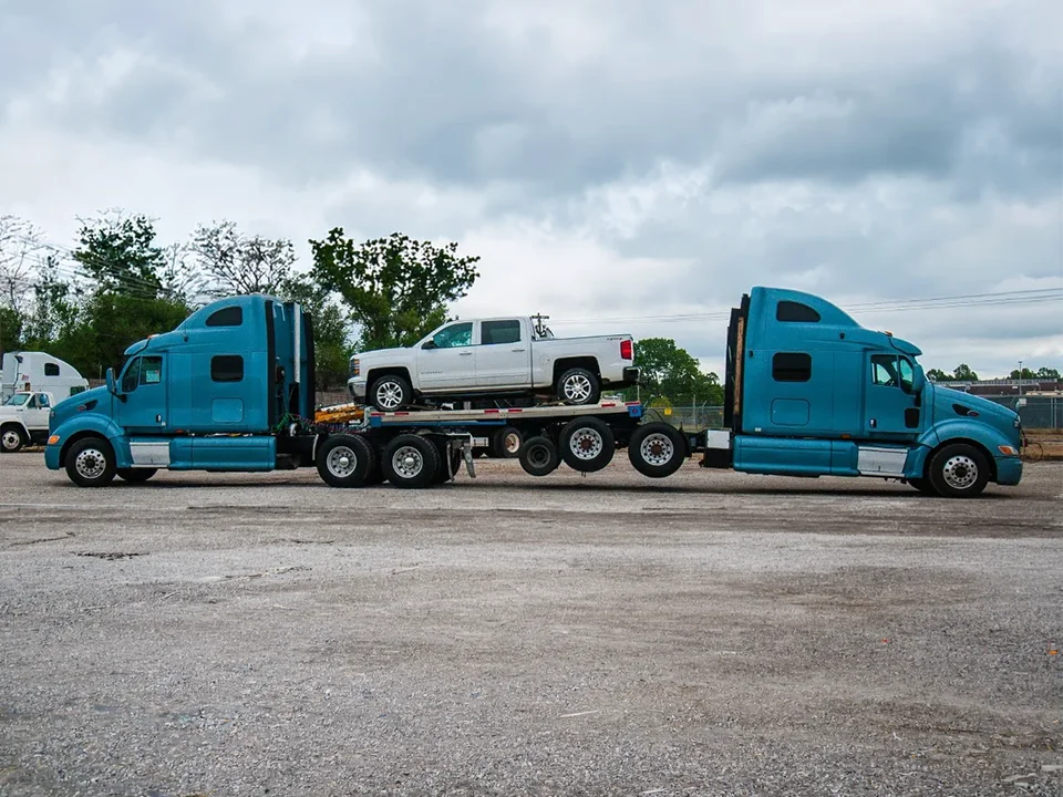 semi truck with a second semi truck and pickup truck in tow