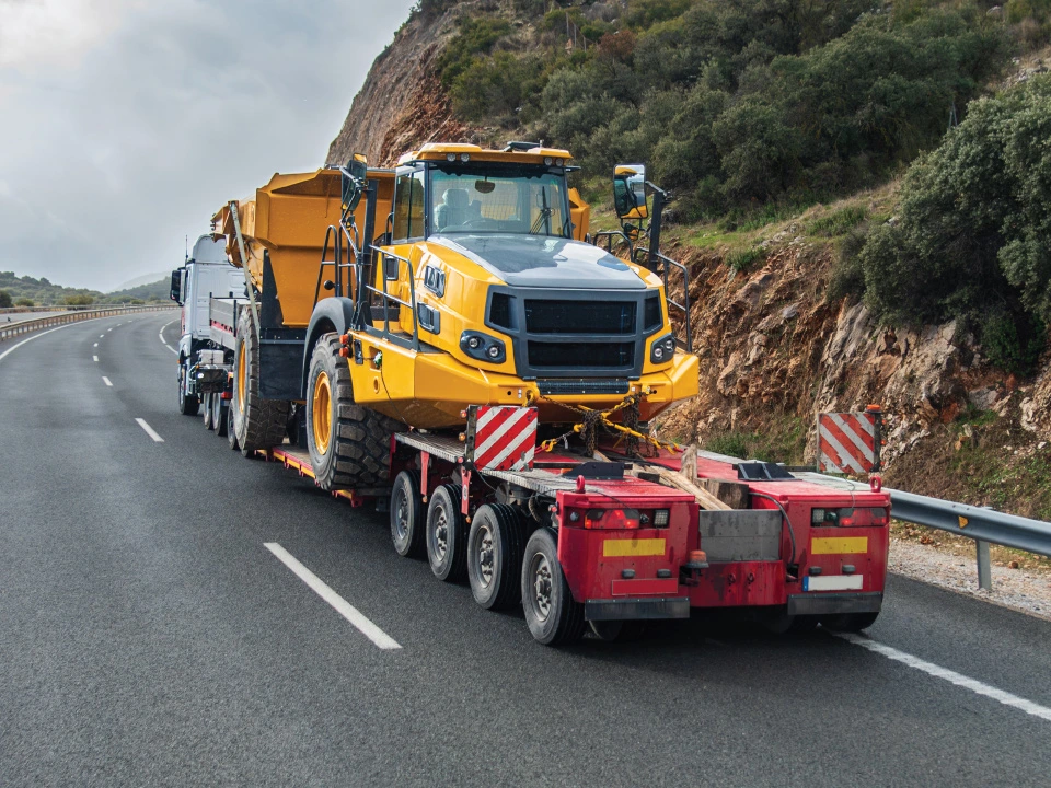 large machinery being transported via trailer by licensed CDL driver